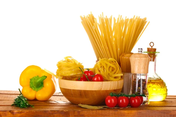 Spagetti, nuudelit kulhossa, purkki öljyä ja vihanneksia puupöydällä isola — kuvapankkivalokuva