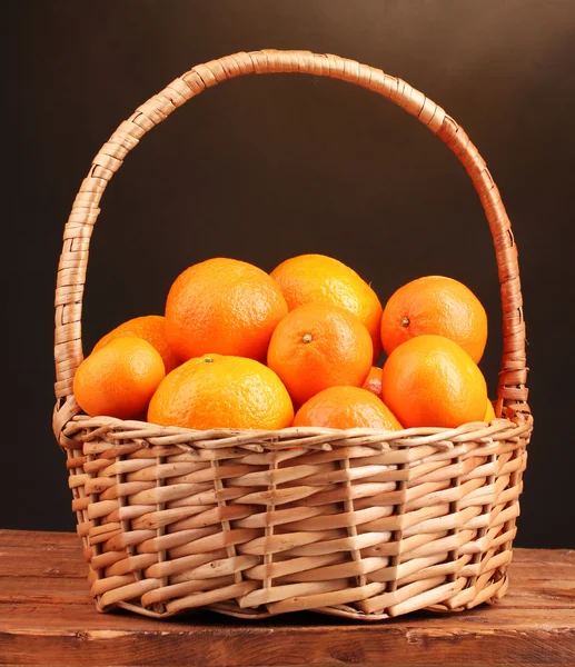 Mandarinen in einem schönen Korb auf Holztisch auf braunem Hintergrund — Stockfoto