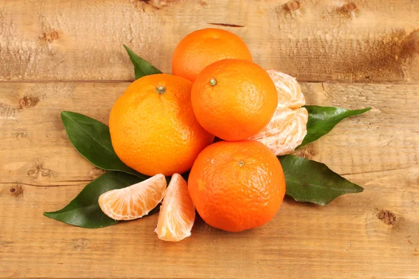 Mandarini con foglie su tavolo di legno — Foto Stock