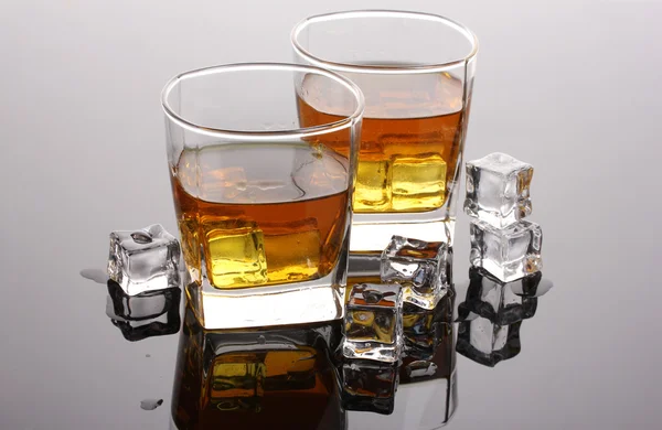 Two glasses of scotch whiskey and ice on grey table — Stock Photo, Image
