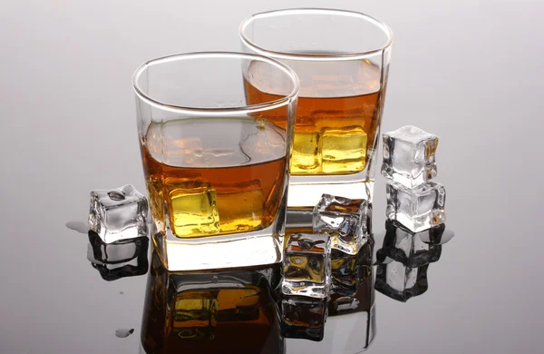 stock image Two glasses of scotch whiskey and ice on grey table