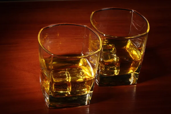 Δύο ποτήρια σκοτσέζικο ουίσκι και το πάγο σε ξύλινο τραπέζι — Φωτογραφία Αρχείου