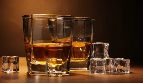 Zwei Gläser Scotch Whiskey und Eis auf Holztisch auf braunem Hintergrund — Stockfoto
