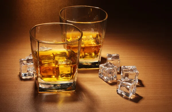 Dos vasos de whisky escocés y hielo sobre mesa de madera —  Fotos de Stock