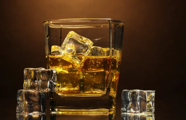 Sklo skotské whisky a ledu na hnědé pozadí — Stock fotografie