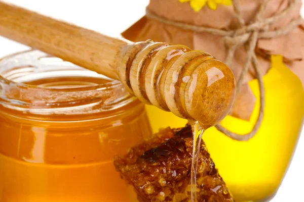 Two jars of honey, honeycombs and wooden drizzler closeup Royalty Free Stock Images