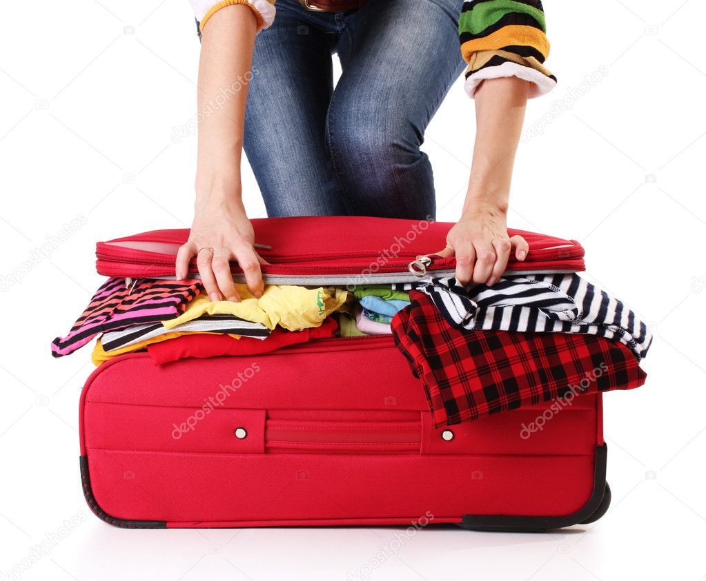 A girl tries to close the suitcase isolated on a white