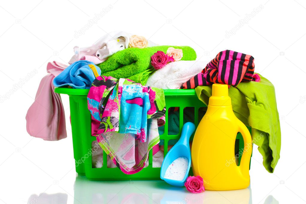 Clothes with detergent and washing powder in green plastic basket isolated