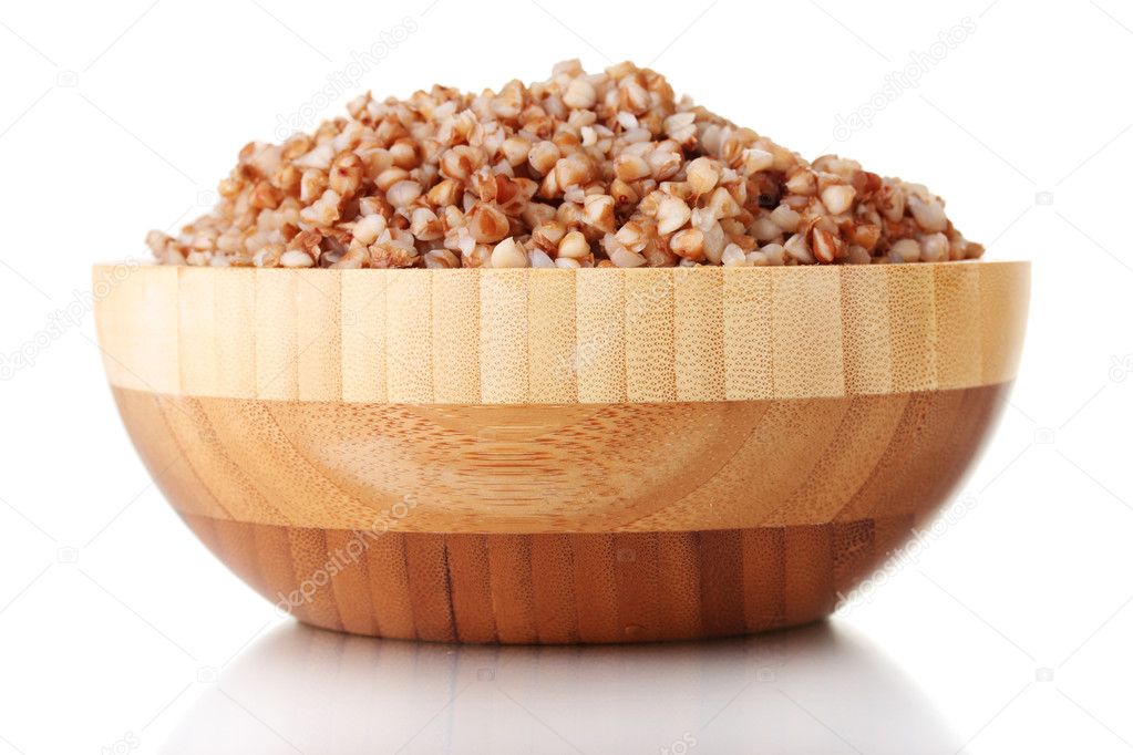 Boiled buckwheat in a wooden bowl isolated on white