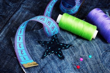 Star-shaped patch on jeans with threads and buttons closeup clipart