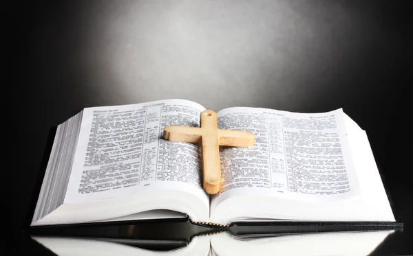 Russische offene Heilige Bibel mit Holzkreuz auf schwarzem Hintergrund — Stockfoto