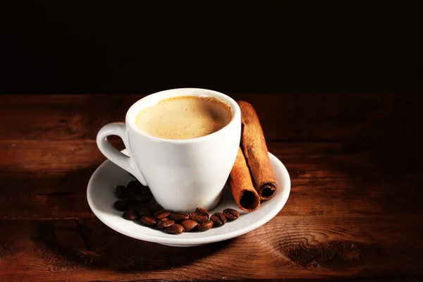 Kopp med kaffe, kanel og kaffebønner på trebord på brun bakgård – stockfoto