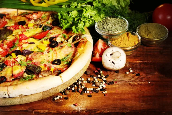 stock image Delicious pizza, vegetables and spices on wooden table