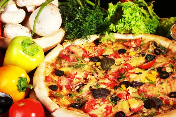 Délicieuse pizza, légumes et épices sur table en bois — Photo
