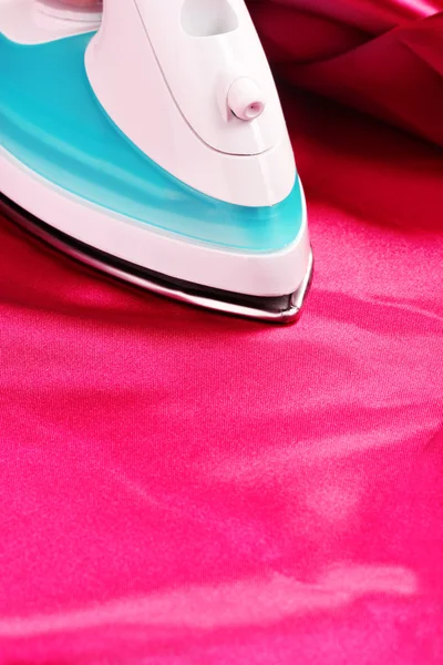 Electric iron on red cloth closeup — Stock Photo, Image