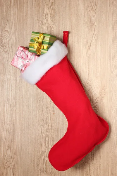 Christmas sock with gifts on wooden background — Stock Photo, Image