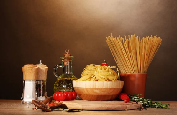 Spaghettis, nouilles dans un bol, bocal d'huile et légumes sur table en bois sur br — Photo
