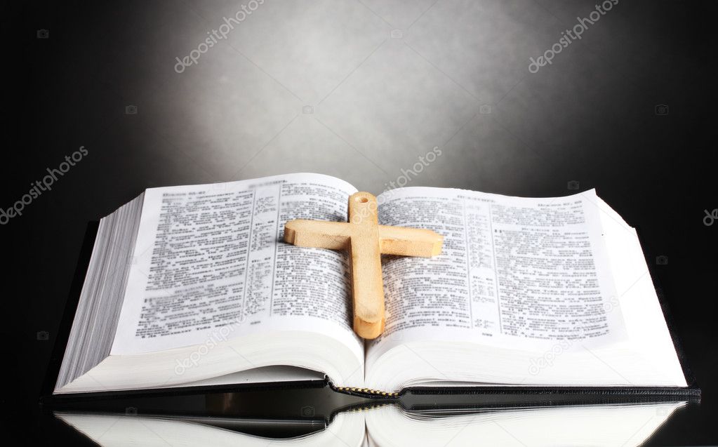 Russian open holy bible with wooden cross on black backround