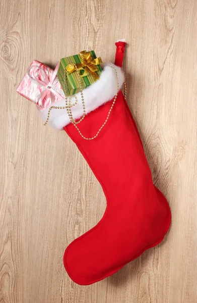 Skarpetka świąteczna z prezentami na drewnianym tle — Zdjęcie stockowe