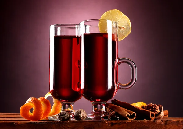 Mulled wine in the glasses, spice and lemon on purple background — Stock Photo, Image