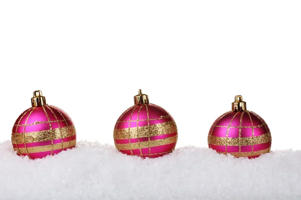 Hermosas bolas de Navidad de color rosa en la nieve aislada en blanco — Foto de Stock