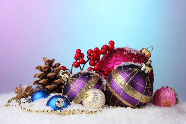 Красиві різдвяні кульки і шишки на снігу на яскравому фоні — стокове фото