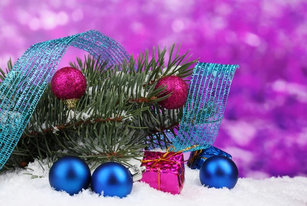 Grüner Weihnachtsbaum mit Spielzeug und Schleife im Schnee auf lila — Stockfoto