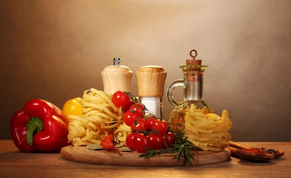 Nudlar i skål, burk med olja, kryddor och grönsaker på träbord på brown — Stockfoto