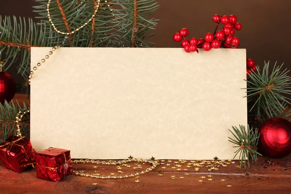 Lege briefkaart, kerstballen en Spar-boom op houten tafel op bruine backg — Stockfoto