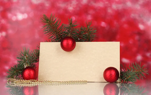 Prázdná pohlednice, vánoční koule a jedle na červeném pozadí — Stock fotografie