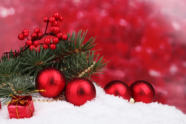 Різдвяний м'яч та іграшка з зеленим деревом у снігу на червоному — стокове фото