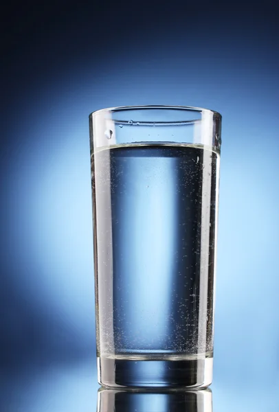 Склянка води на синьому фоні — стокове фото