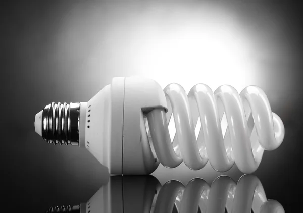 Энергосберегающая лампа на сером фоне — стоковое фото