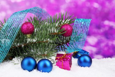 Green Christmas tree with toy and ribbon in the snow on purple clipart