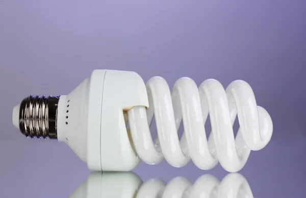 Lampadina a risparmio energetico su sfondo viola — Foto Stock