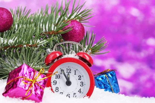 Green Christmas tree with toy and clock in the snow on purple — Stock Photo, Image