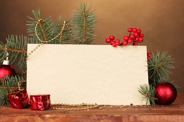 Blank postcard, Christmas balls and fir-tree on wooden table on brown backg — Stock Photo, Image