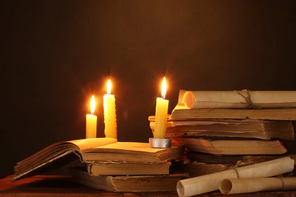 Pilha de livros antigos com vela e pergaminho no escuro — Fotografia de Stock