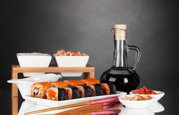 Köstliches Sushi auf Teller, Essstäbchen, Sojasauce, Fisch und Garnelen auf grauem Fleisch — Stockfoto