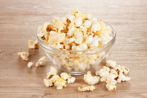 Popcorn w szklanej misce na drewnianym stole — Zdjęcie stockowe