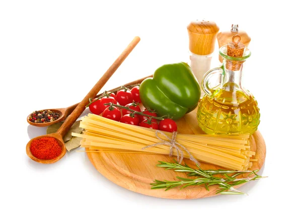 Спагетти, банка с маслом, специи и овощи на деревянной доске изолированы на WH — стоковое фото