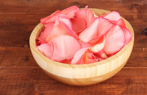 Красивые розовые лепестки роз в деревянной чаше на столе — стоковое фото
