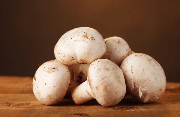 stock image Champignons mushrooms in basket on wooden table on brown background