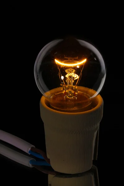 Eine beleuchtete Glühbirne auf schwarzem Hintergrund — Stockfoto
