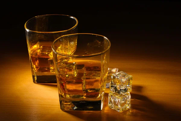 Δύο ποτήρια σκοτσέζικο ουίσκι και το πάγο σε ξύλινο τραπέζι — Φωτογραφία Αρχείου