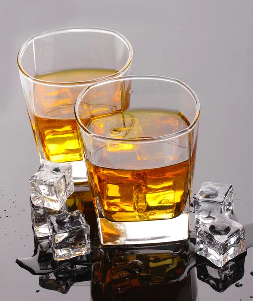 Dwie szklanki szkockiej whisky i lód na szarym stole. — Zdjęcie stockowe