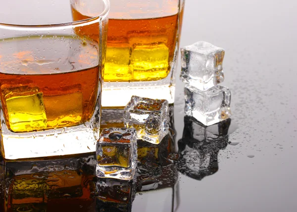 stock image Two glasses of scotch whiskey and ice on grey table