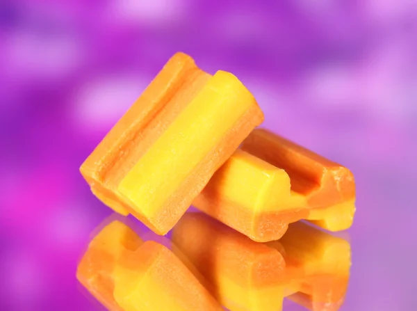 Läckra tuggummi på lila bakgrund — Stockfoto