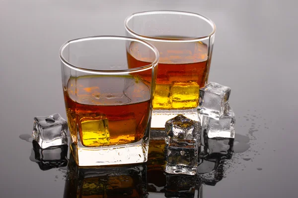 两杯威士忌和冰块在灰色的桌子上 — 图库照片