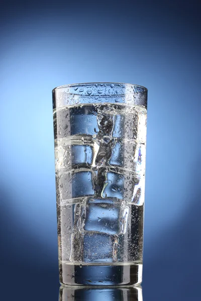 Vaso de agua con hielo sobre fondo azul — Foto de Stock